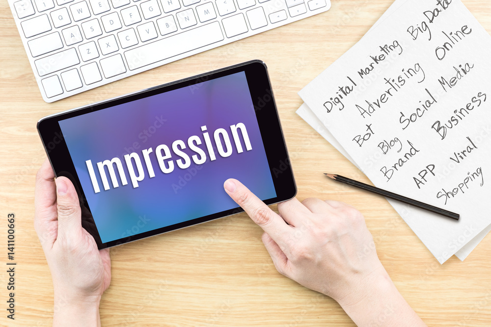 Poster Hand using tablet with Impression word on screen with list of digital marketing features on paper on work table,Online business concept