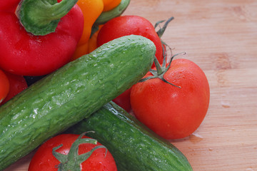 Paprika, tomatoes, cucumber fresh and washed on a wooden board