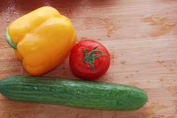 Paprika, tomatoes, cucumber fresh and washed on a wooden board