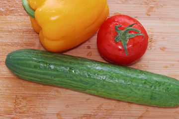 Paprika, tomatoes, cucumber fresh and washed on a wooden board
