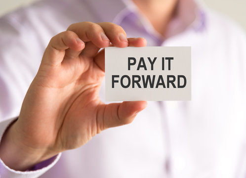 Businessman holding a card with PAY IT FORWARD message
