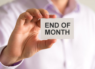 Businessman holding a card with END OF MONTH message