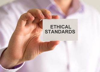 Businessman holding a card with ETHICAL STANDARDS message
