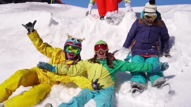 Cheerful rest with friends in ski resort. Young girls I ride on snow from mountain top.