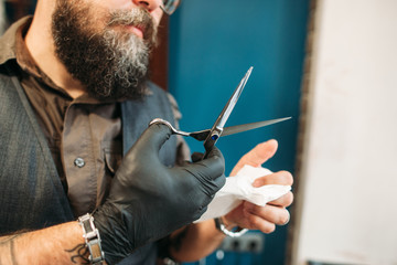 Haircut instruments disinfection after work. Closeup on barber hands holding Scissors and...