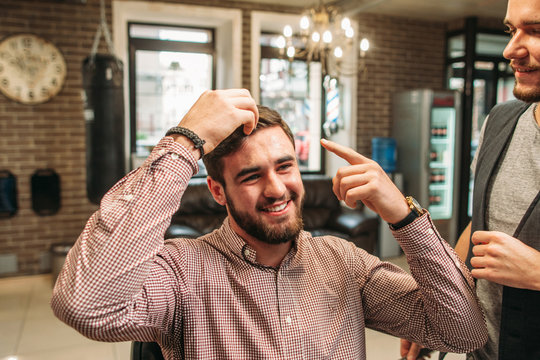 Confident smiling man show his hair free space. Laughing businessman sitting at barber shop before haircut. Beauty, modern life, fashion concept
