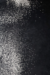 Sift flour from a sieve on black background