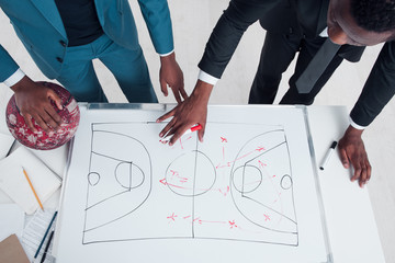 Two african basketball coaches plan and discuss new game strategy. Trainers making scheme of...