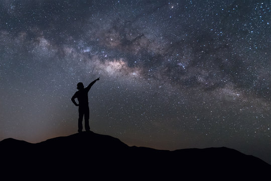 Milky Way landscape. Silhouette of Happy woman standing on top of mountain with night sky and bright star on background.