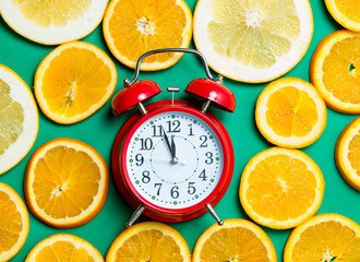 photo of cute alarm clock near dried orange slices on the wonderful turquoise background