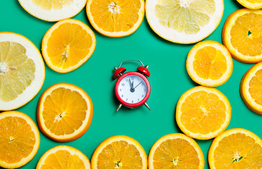 Naklejka na ściany i meble photo of cute alarm clock near dried orange slices on the wonderful turquoise background