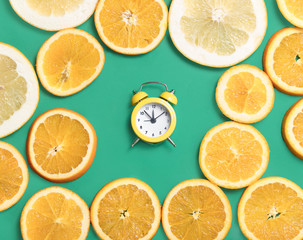 Fototapeta na wymiar photo of cute alarm clock near dried orange slices on the wonderful turquoise background