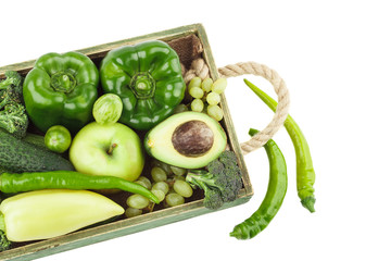 Set of different green fresh raw vegetables and fruits in the wooden tray