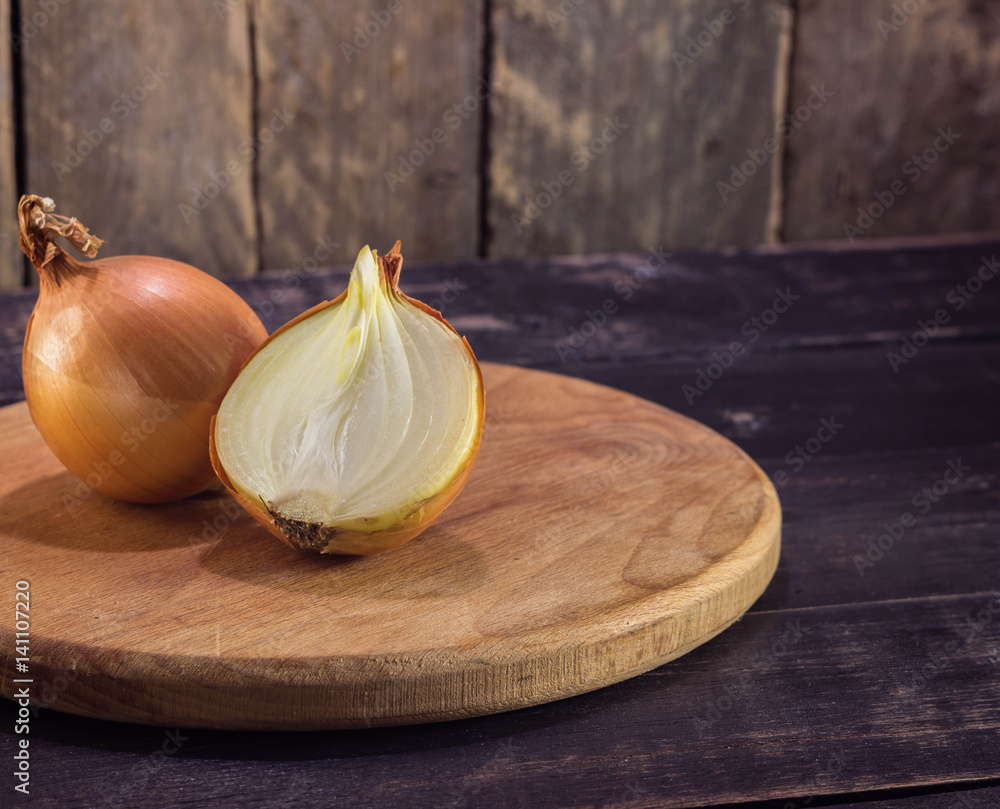 Wall mural two ripe sliced onion with knife on rustic wooden background