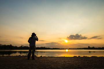 Silhouette photographer in sunset background