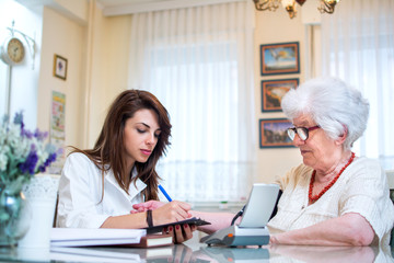 Caregiver examining blood pressure for senior patient at home.