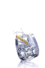 orange splashing into glass of water on white background