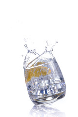 orange splashing into glass of water on white background
