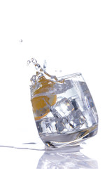 orange splashing into glass of water on white background