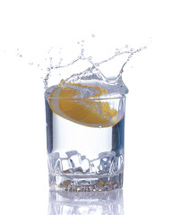 orange splashing into glass of water on white background