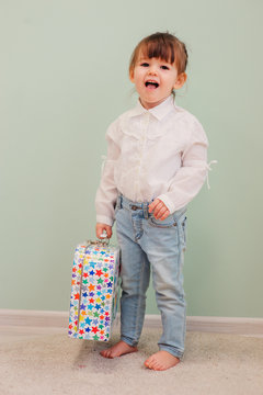 indoor portrait of cute happy baby girl playing with toy suitcase