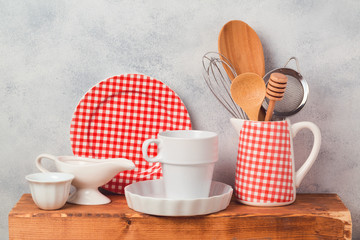Kitchen utensils and dishware on wooden board over rustic background