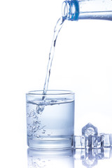 Water is poured into a glass with ice cubes