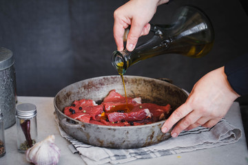 Cutting raw beef meat with knife on a cutting board. Chef add olive oil on beef meat goulash.