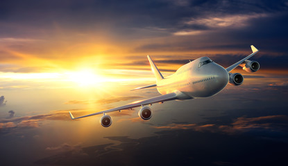 Naklejka na ściany i meble Airplane flying above clouds during sunset