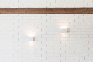 White brick wall with two lights and wooden beam