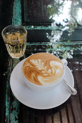Hot Latte on Wooden Glass-Topped Coffee Table Outside