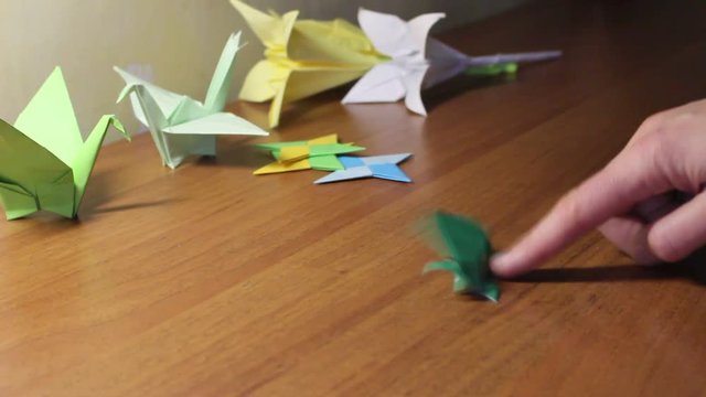 Hands Of Child Folding Origami Frog With Green Paper