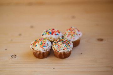 Easter cupcakes with cream and small confetti on a wooden table. Spring.