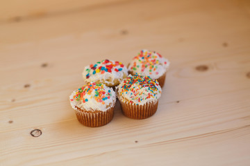 Easter cupcakes with cream and small confetti on a wooden table. Spring.