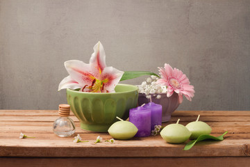 Fototapeta na wymiar Spa and wellness concept with flowers in bowls and candles on wooden table over rustic background