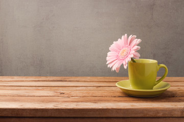 Spring concept with flower in coffee cup over rustic background