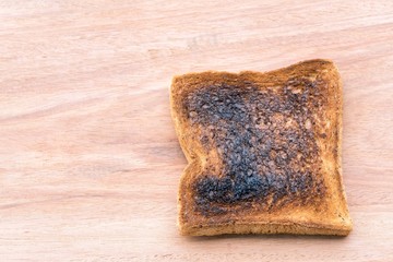 Close-up of burnt toast ON wooden background with copy space.