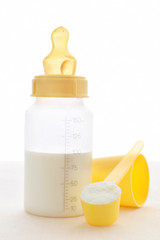 Babynahrung Pulver in Messlöffel und vorbereiteter flüssiger  Milch in Plastikflasche mit Sauge