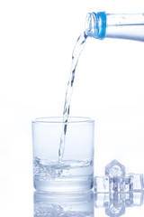 Water is poured into a glass with ice cubes