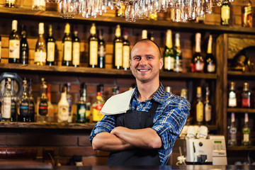 Barman at work in pub,Portrait of cheerful barman worker standing,Waiter giving menus,A pub.Bar.Restaurant.Classic.Evening.European restaurant.European bar.American restaurant.American bar.