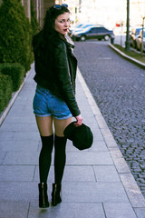 Stylish modern woman in old part of city in short shorts and a leather jacket
