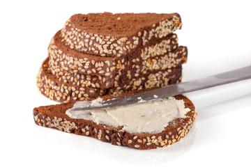 slices of black bread with sesame seeds and butter isolated on white background