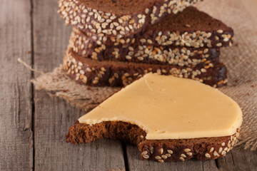 slices of black bread with sesame seeds and cheese on the old wooden background