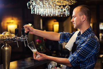 Bartender pouring the fresh beer in pub,barman hand at beer tap pouring a draught lager beer,beer from the tap,Filling glass with beer,fresh beer,pub.Bar.Restaurant.European bar.American bar.