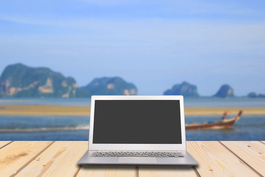 Laptop with blank screen on wooden table with lake and sea © Goodvibes Photo