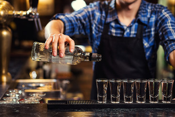 Barman at work,Barman pouring hard spirit into glasses in detail,Bartender is pouring tequila into glass,preparing cocktails,concept about service and beverages - obrazy, fototapety, plakaty