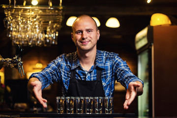 Barman at work,Barman pouring hard spirit into glasses in detail,Bartender is pouring tequila into...