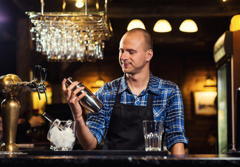 Barman at work,Barman pouring hard spirit into glasses in detail,Bartender is pouring tequila into glass,preparing cocktails,concept about service and beverages
