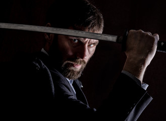 stern angry businessman in a wool coat with sword in dark background