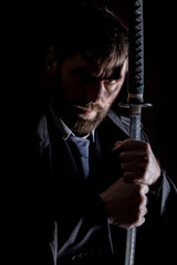 stern angry businessman in a wool coat with sword in dark background